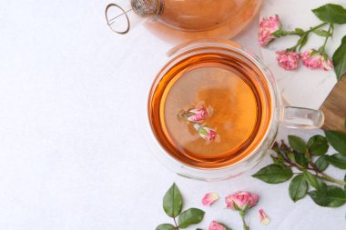 Cam fincanda romatik çay, çaydanlık, güller ve yeşil yapraklar ışık masasında, düz yerde. Metin için boşluk