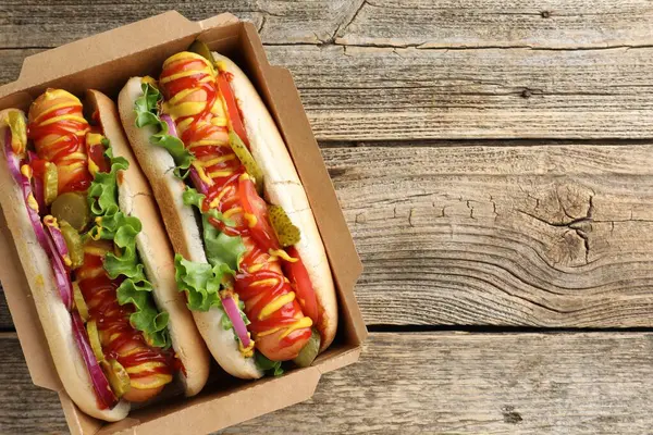 Sebzeli, hardallı ve ketçaplı lezzetli sosisliler, ahşap masa, üst manzara. Metin için boşluk