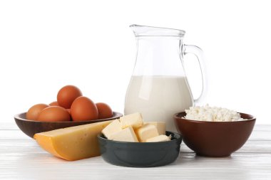 Farklı süt ürünleri ve yumurtalar beyaz arka plana karşı ahşap masa üzerinde