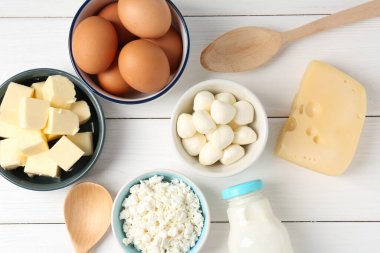 Farklı süt ürünleri ve yumurtalar beyaz ahşap masa üzerinde, düz yatıyordu