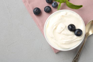 Lezzetli yoğurt kasede, yabanmersini, nane ve kaşık gri masada, düz yerde. Metin için boşluk