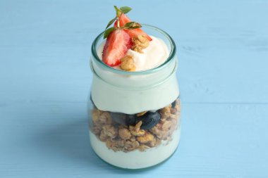 Tahıllı yoğurt ve cam kavanozda böğürtlen açık mavi ahşap masa, yakın çekim