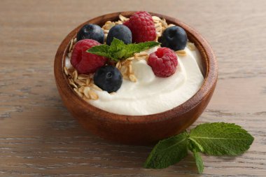 Lezzetli yoğurt, tahıl gevreği ve ahşap masada böğürtlen.