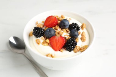 Tahıllı yoğurt ve beyaz mermer masada böğürtlen, yakın plan.