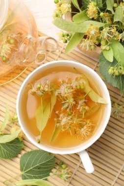 Taze ıhlamur çayı, çaydanlık ve çiçekler beyaz ahşap masada, düz uzanmış