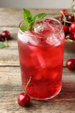 Buzlu vişneli gazoz, böğürtlen ve nane şekeri ahşap masada, yakın plan.