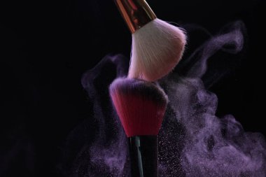 Siyah arka planda mor göz farlı makyaj fırçaları, yakın plan