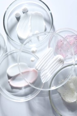Petri kaplarında farklı kozmetik ürünleri beyaz arka planda, yakın planda
