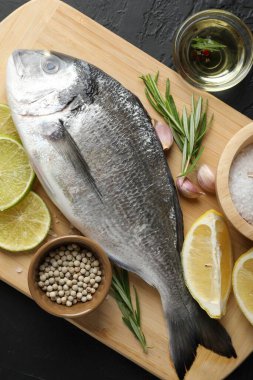 Siyah masadaki baharatlı taze çiğ dourade, üst manzara. Balık ve deniz ürünleri lezzetleri