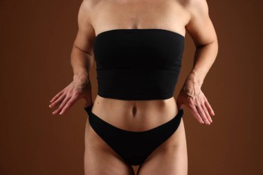 Kahverengi arka planda mükemmel vücudu olan fit bir kadın, yakın plan.