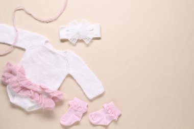 Bej arka planda bebek kıyafetleri ve aksesuarlar, düz yatış. Metin için boşluk