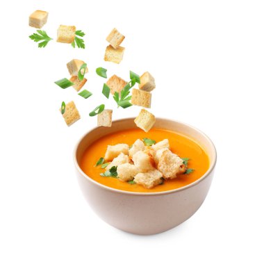 Kırmızılar ve otlar beyaz arka planda bir kase çorbaya dökülüyor.