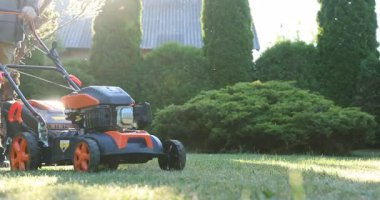 Lviv, Ukrayna - 2 Temmuz 2025: Bahçedeki çim biçme makinesiyle yeşil çim biçen adam, yakın plan