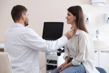 Klinikte kadının tiroid bezini ultrason taraması yapan sonograf.