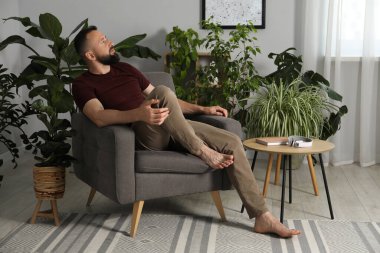 Uyum. Evdeki rahat koltukta dinlenen adam.