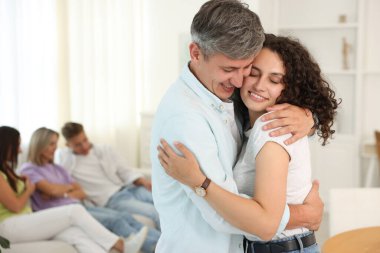 Mutlu arkadaşlar evde sarılıyor, seçici odaklanıyor.