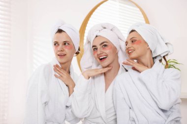 Kapalı alanda yapılan spa ameliyatlarından sonra bornozlu mutlu kadınlar.