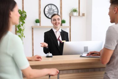 Otel resepsiyonunda müşterilerle çalışan gülümseyen bir resepsiyonist.