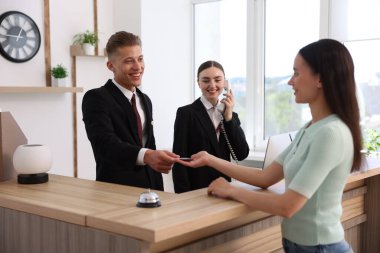 Otel resepsiyonunda resepsiyonist ve müşteri