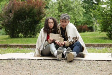 İşaretli evsiz insanlar Parktaki karton kutuda yardım ve kağıt bardak