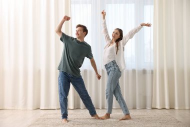 Mutlu genç çift evde dans ediyor.