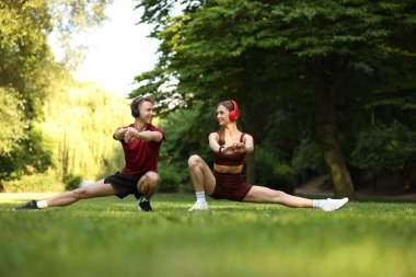 Kulaklıklı mutlu çift parkta sabah egzersizi yapıyor.