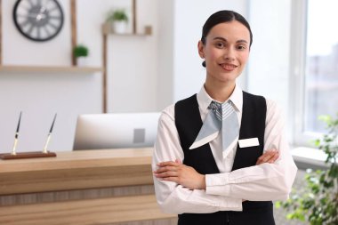 Otelde kollarını kavuşturmuş gülümseyen resepsiyonistin portresi. Metin için boşluk