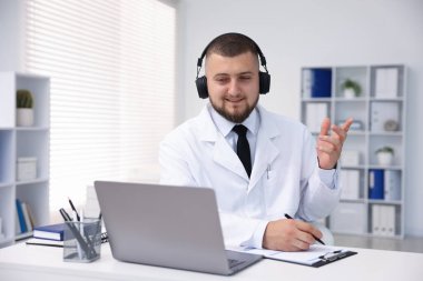 Kulaklıklı doktor içeride bilgisayarla online danışmanlık yapıyor.