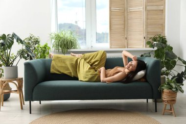 Uyum. Gülümseyen kadın evdeki kanepede dinleniyor.