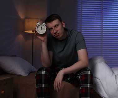Evde uykusuzluk çeken, alarmlı sinirli bir adam.