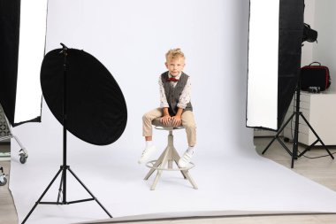 Beyaz arka plandaki küçük çocuk profesyonel ekipmanlarla fotoğraf stüdyosunda.