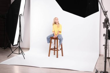 Beyaz arka plandaki küçük kız profesyonel ekipmanlarla fotoğraf stüdyosunda.