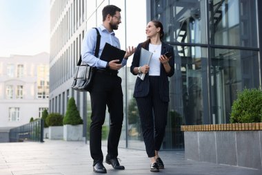 Mutlu iş arkadaşları ofis binasının yakınında bir şeyler tartışıyor.