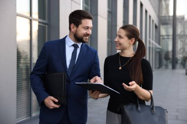 Mutlu iş arkadaşları ofis binasının yakınında bir şeyler tartışıyor.
