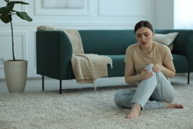 Diz ağrısı çeken kadın evinde yerde yatıyor, mesaj için yer var.