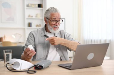 Hapları olan kıdemli bir adam içeride bilgisayarla doktorla görüşüyor.