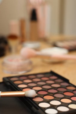 Göz farı paleti ve ahşap masada fırça, yakın plan.