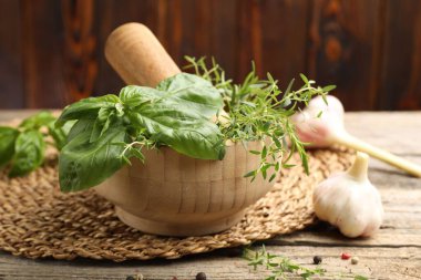 Kabuklu havan, farklı aromatik otlar ve baharatlar ahşap masada, yakın plan.