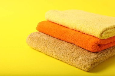 Sarı arka planda renkli havlular yığını, yakın plan. Metin için boşluk