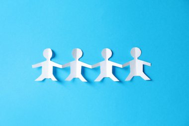 Açık mavi arka planda el ele tutuşan insanların kağıt figürleri.