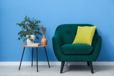 Mavi duvarın yanında rahat bir koltuk ve dekor.