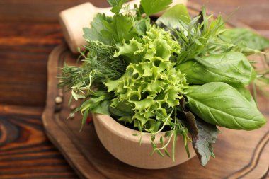 Kabuklu havan, farklı aromatik otlar ve baharatlar ahşap masada, yakın plan.