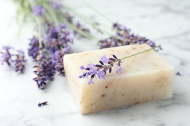 Sabun çubuğu ve lavanta çiçekleri beyaz mermer masada, yakın plan.