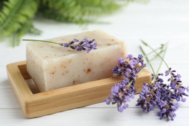 Sabun barı ve lavanta çiçekleri beyaz ahşap masada, yakın plan.