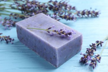 Aromatik sabun barı ve lavanta çiçekleri açık mavi ahşap masa üzerinde, yakın plan.