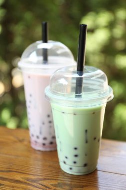 Tahta masada plastik bardaklarda lezzetli sütlü çay, yakın plan.