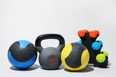 İlaç topları, kettlebell ve açık gri arkaplanda dambıllar
