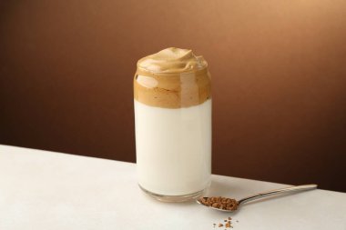 Bardakta lezzetli dalgona kahvesi ve beyaz masada granüller.