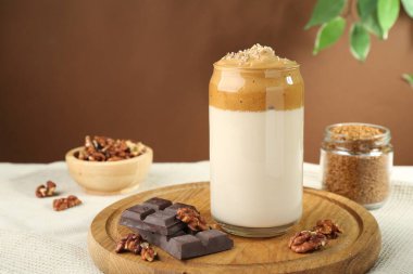 Bardakta lezzetli dalgona kahvesi, çikolata parçaları, ceviz ve granüller masada, yakın plan.