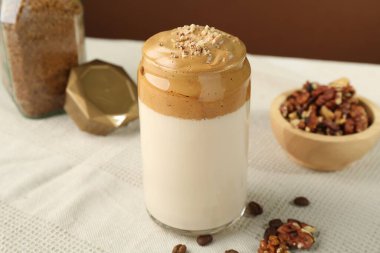 Bardakta lezzetli dalgona kahvesi, fasulye, ceviz ve granüller masada, yakın plan.